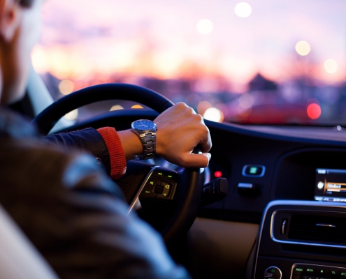 Chauffeur élégant au volant d'une voiture VTC au crépuscule